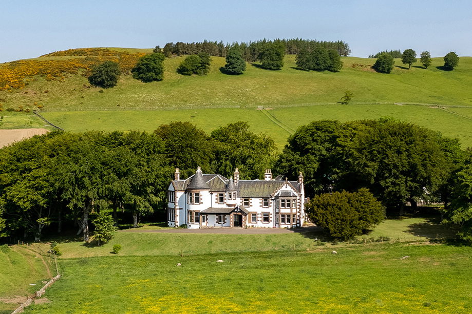 Exterior of Kinclune House with rolling green hills in background